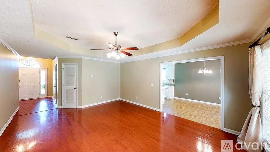 A spacious room with wood flooring and a ceiling fan.