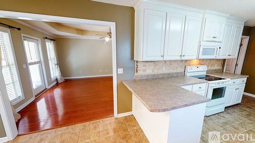 A kitchen with white cabinets and a countertop is available for rent.