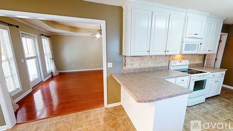 A kitchen with white cabinets and a countertop is available for rent.