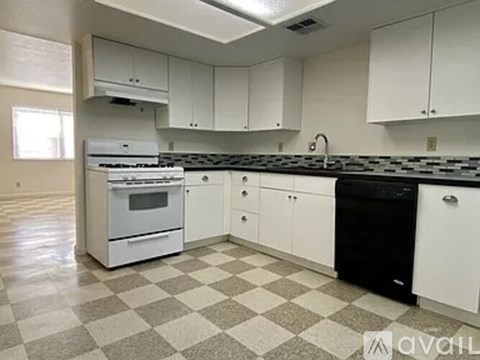 A kitchen with white cabinets and a black and white checkered floor.