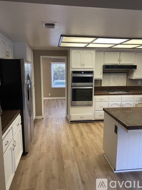 A kitchen with white cabinets and a black fridge.
