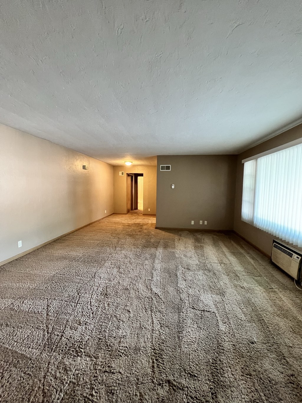 an empty living room with a large window and carpet