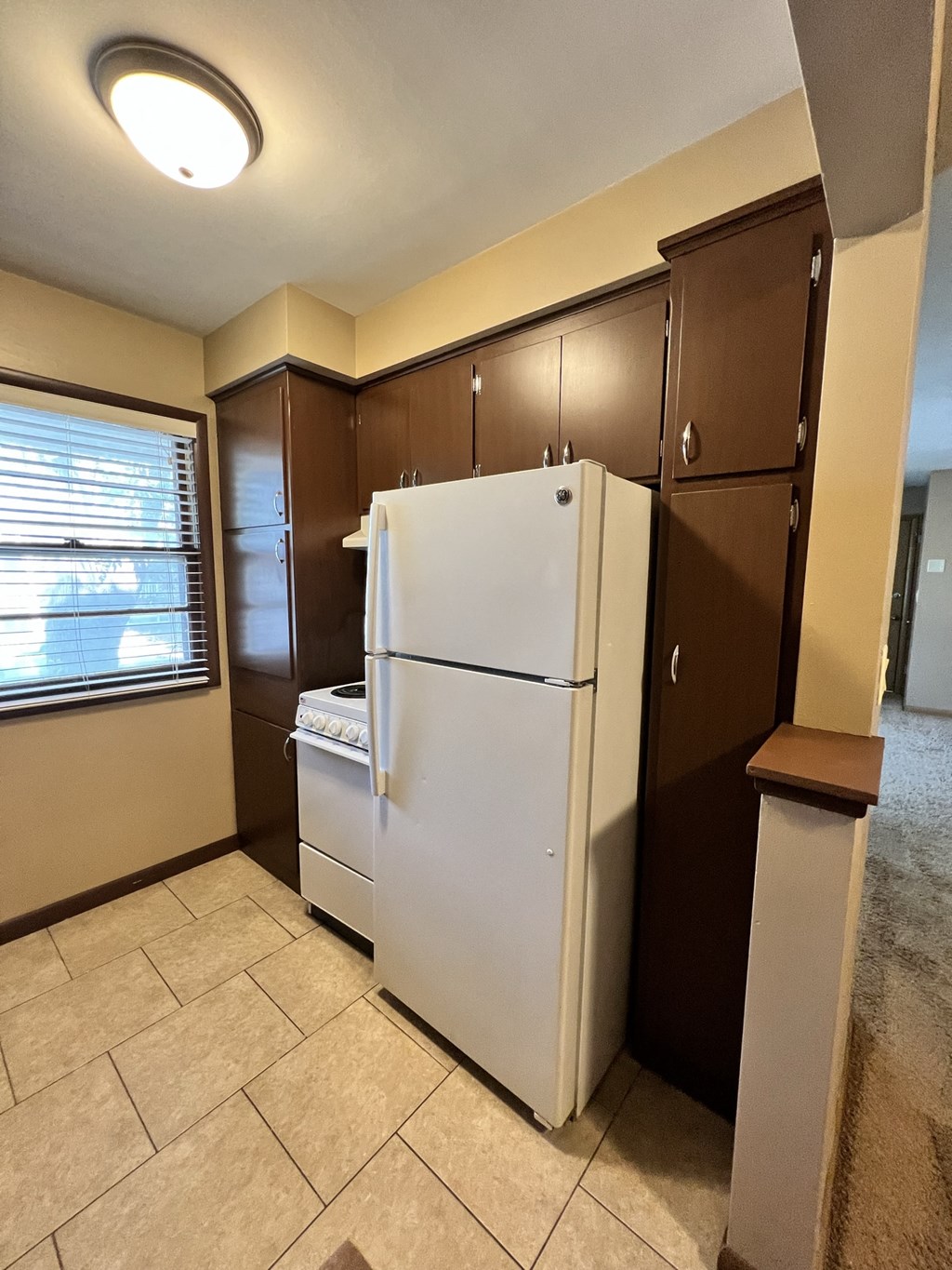 a kitchen with a refrigerator and cabinets and a window