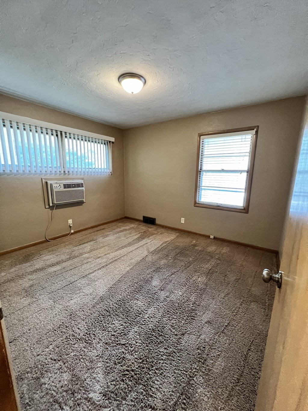 an empty living room with a carpeted floor and a window