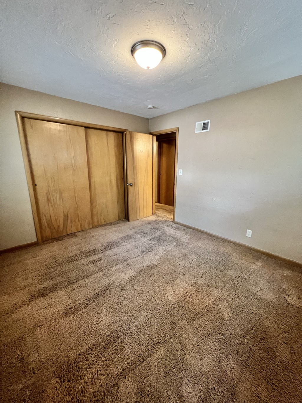an empty living room with carpet and a door to a closet