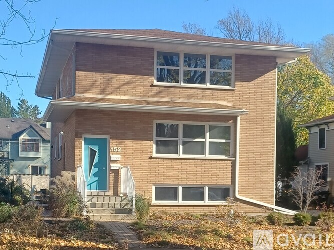 A two-story house with a blue door and a brick facade.