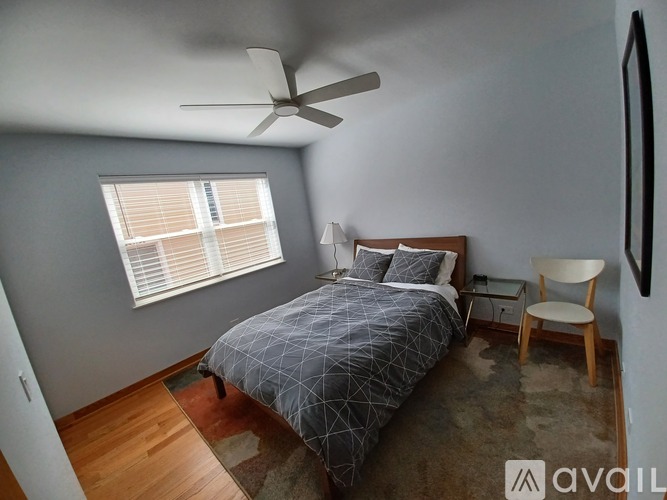 A bedroom with a bed, chair, and ceiling fan.