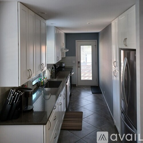 A kitchen with white cabinets and a black counter top.