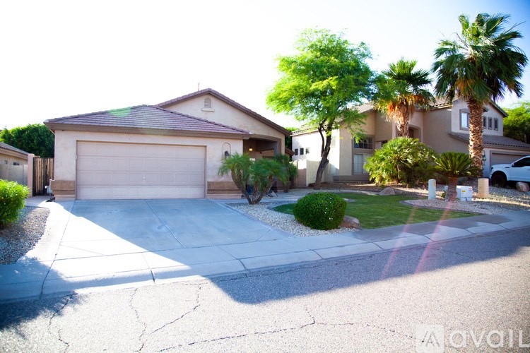 A house with a driveway and a palm tree in front.