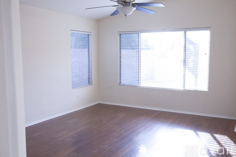 A room with a ceiling fan and a window with blinds.