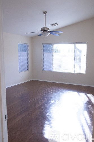 A room with a ceiling fan and wooden floors.