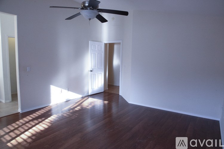 A room with a ceiling fan and a door in the middle.