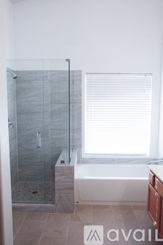 A bathroom with a glass shower stall and a bathtub.