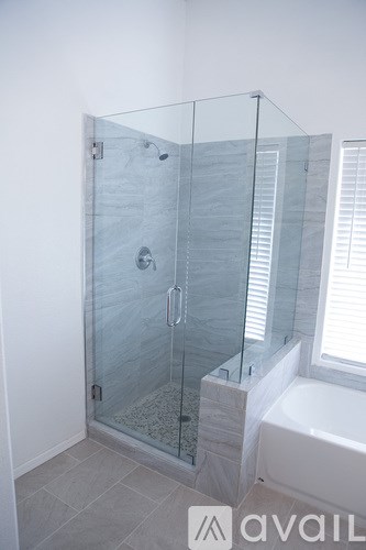 A glass shower stall with a glass door and a glass enclosed shower head.