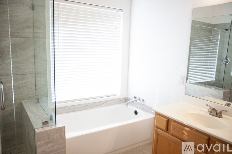 A bathroom with a tub, sink, and mirror.