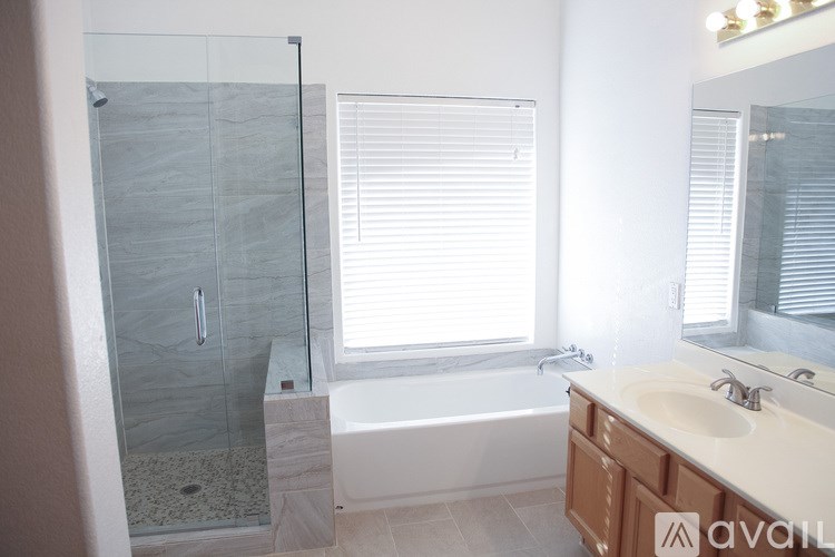 A bathroom with a glass shower stall, a bathtub, and a sink.