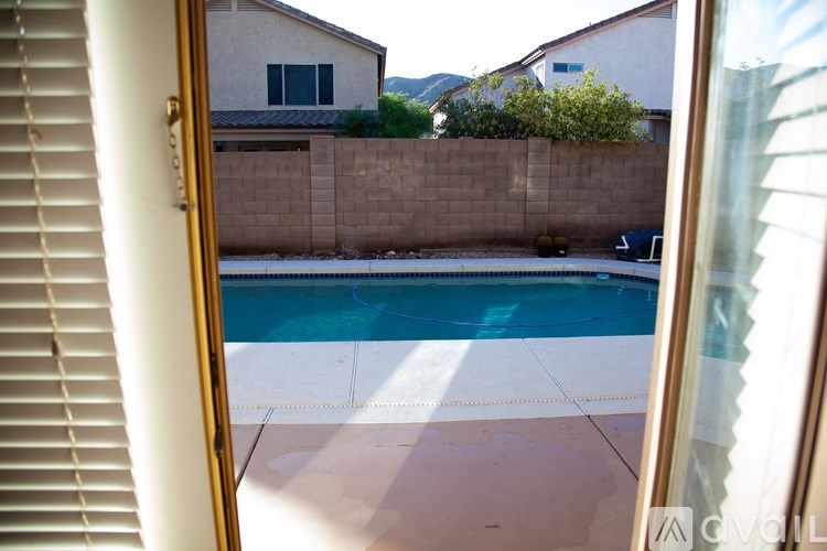 A pool in a backyard with a house and a wall in the background.
