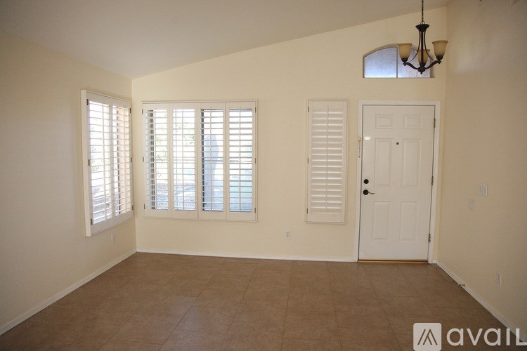 A room with a door, a window with shutters, and a chandelier.