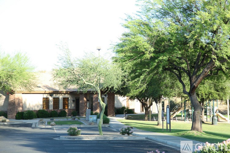 A tree in a park is taller than the building behind it.