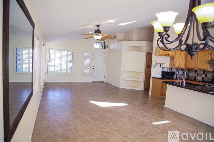 A spacious room with a ceiling fan and a kitchen area with a counter and cabinets.