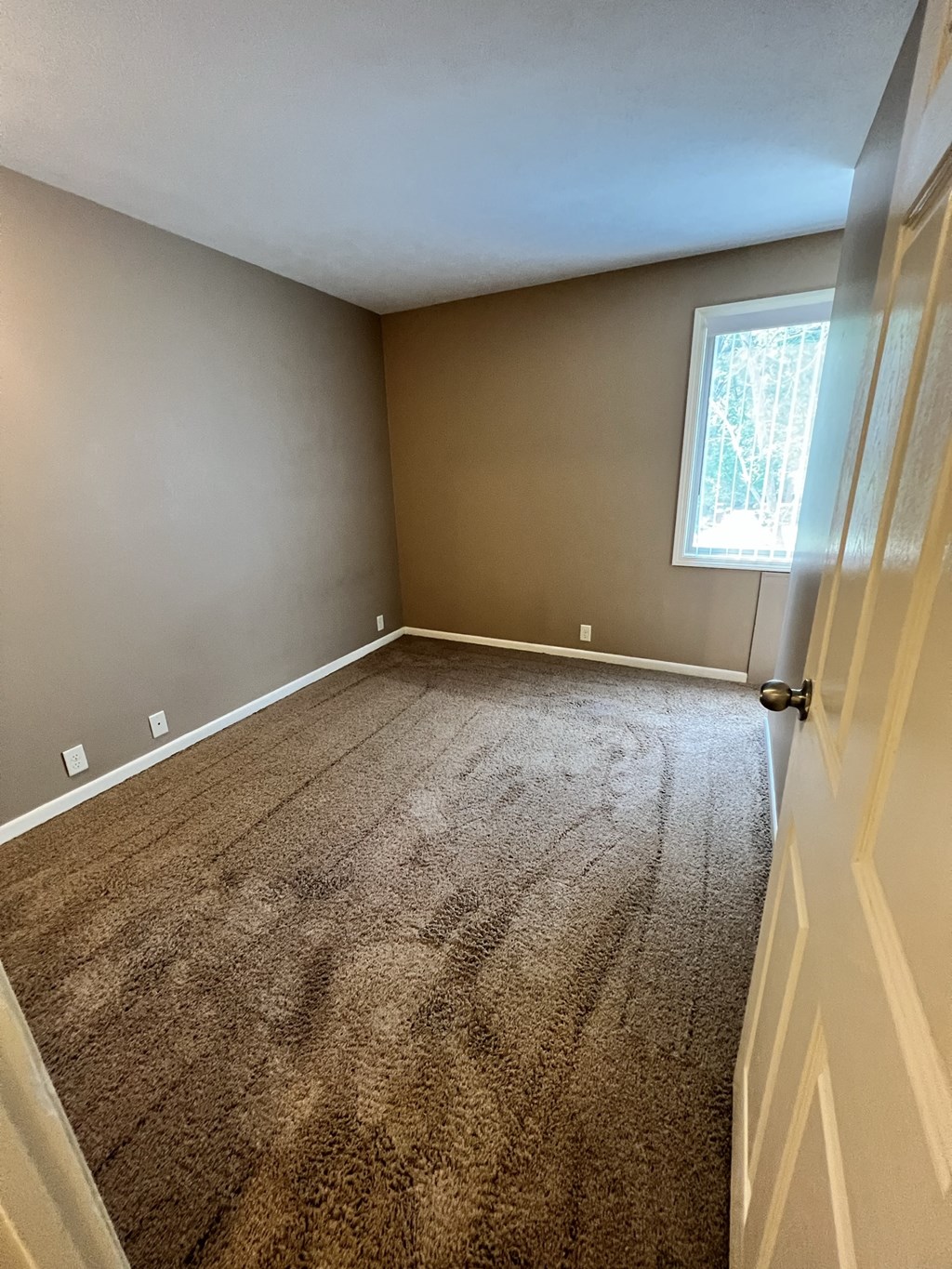 an empty bedroom with a carpeted floor and a window
