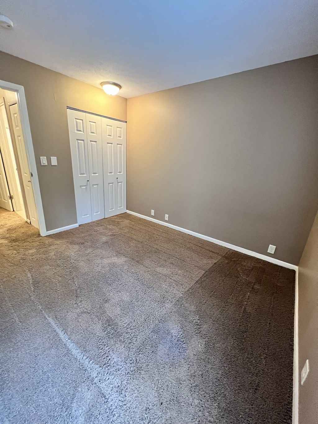 a empty living room with a carpeted floor and a door