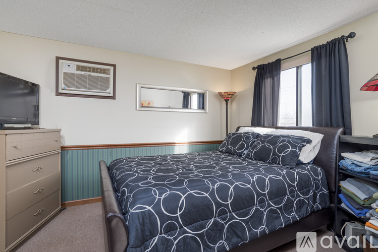 A bedroom with a bed, dresser, and window.