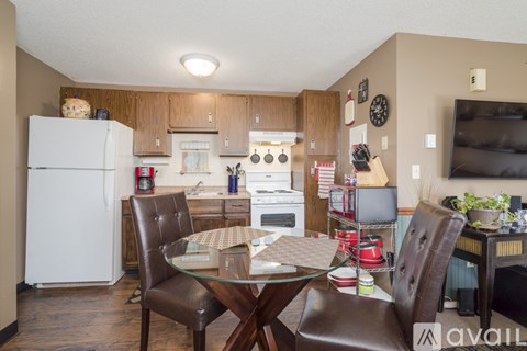 A kitchen with a white refrigerator and brown chairs.