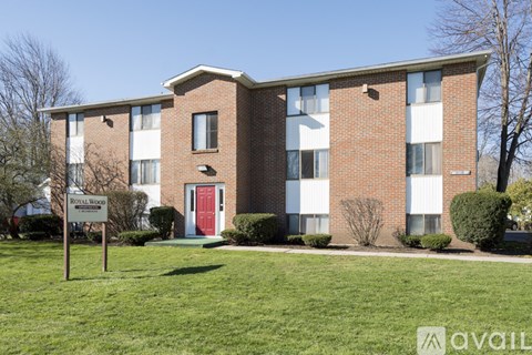 A brick building with a red door and a sign that says "Available".