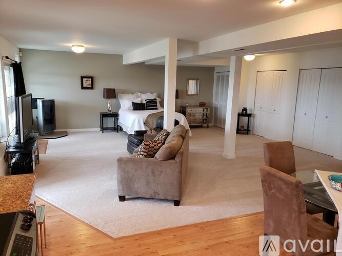 A living room with a couch, chairs, and a television.