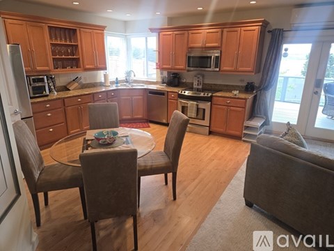 A kitchen with wooden cabinets and a glass table with four chairs.