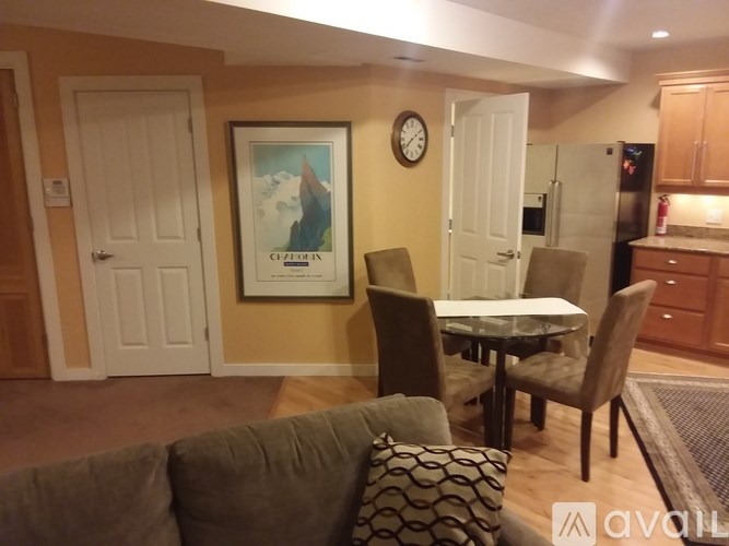 A living room with a couch, chairs, and a painting on the wall.