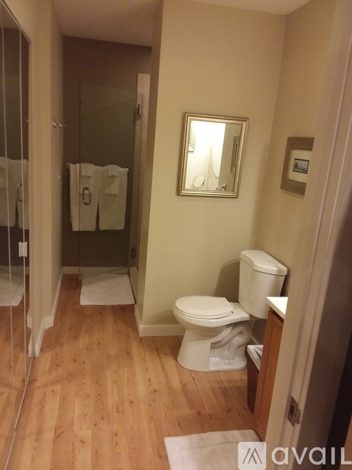 A bathroom with a toilet, sink, mirror and shower.