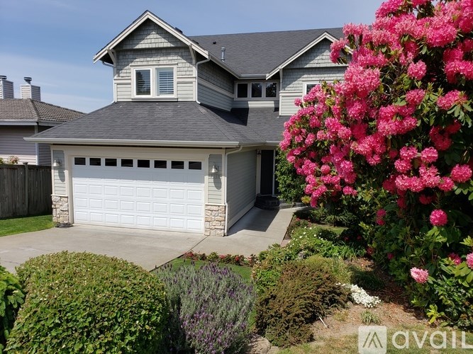 A house with a garage and a garden with pink flowers.