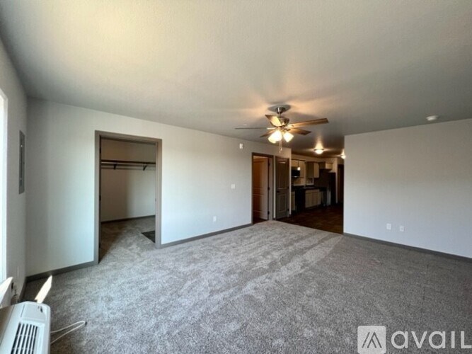 A spacious room with a ceiling fan and carpeted floor.