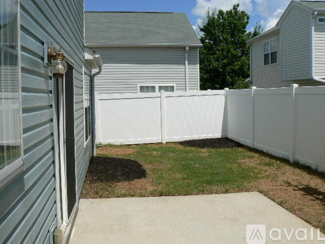 A white fence separates a house from a grassy area.