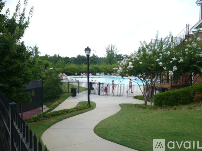A walkway with a lamp post and a pool in the distance.