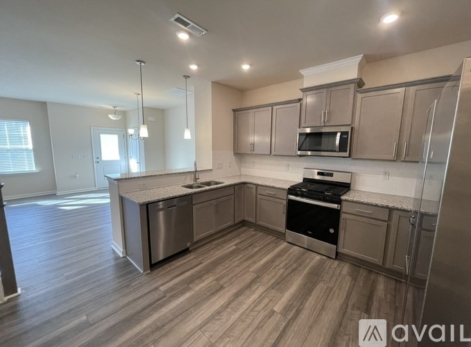 A modern kitchen with wooden floors and stainless steel appliances.