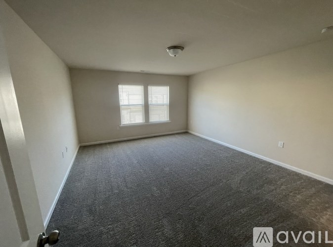 A room with a carpeted floor and a window with blinds.