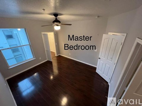 A spacious master bedroom with a ceiling fan and hardwood flooring.