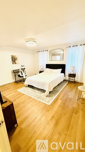 A bedroom with a bed, chair, and mirror.