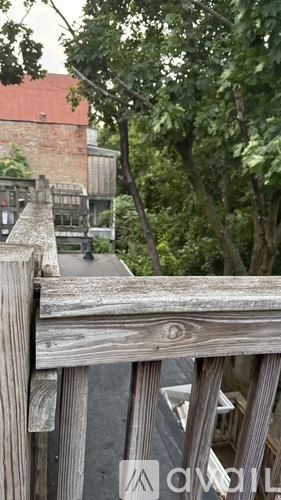 A wooden fence in the foreground with a building and trees in the background.