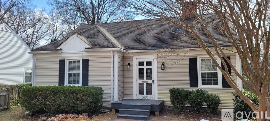 A small house with a white door and black shutters is for sale.
