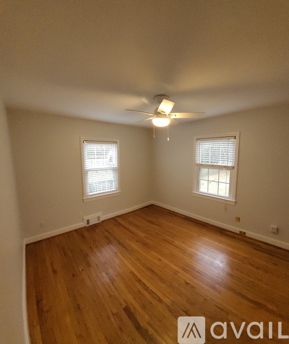 A room with wooden floors and two windows.