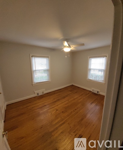 A room with wooden floors and two windows.