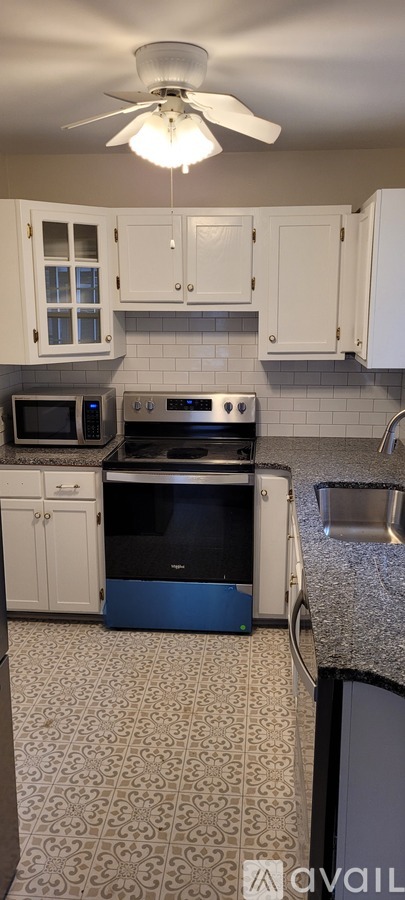 A kitchen with white cabinets and a black stove top oven.