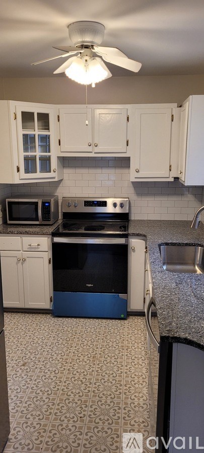 A kitchen with white cabinets and a black stove top oven.