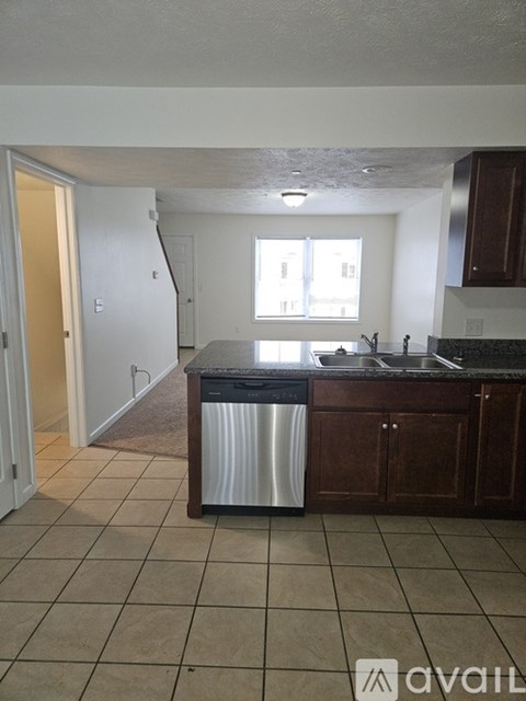A kitchen with a black counter top and a stainless steel dishwasher.