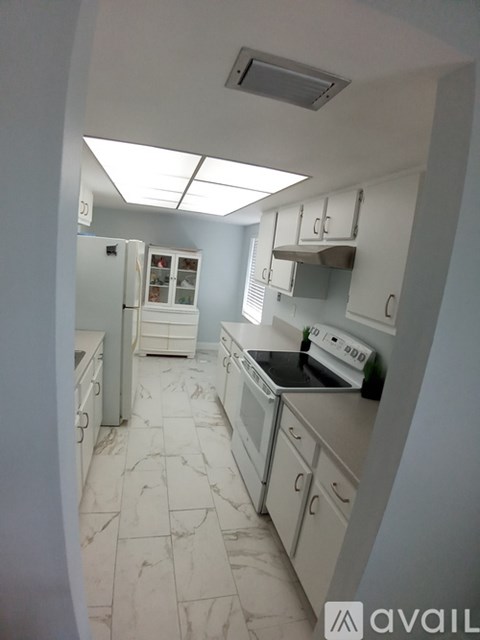A kitchen with white cabinets and a marble floor.