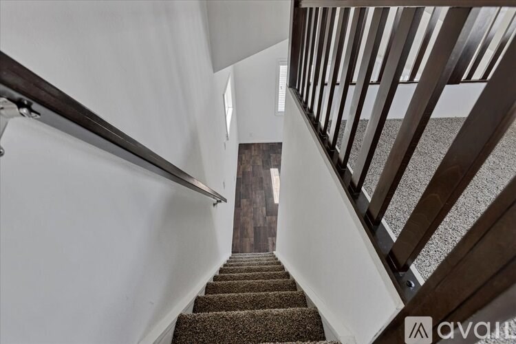 A staircase with a metal railing and a carpeted runner leads to a door at the end.